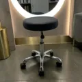 Professional hairdressing stool - Rolling beauty stool - Saddle stool - Sit-stand professional stool - Hairdressing and beauty furniture - Ergonomic stool with backrest - Gas lift height adjustment - High-density resilient foam - Chrome star base - Hair-resistant casters - Barber cutting stool - Tattoo artist stool - Massage and treatment chair - Manicure and pedicure stool - Washable faux leather upholstery
